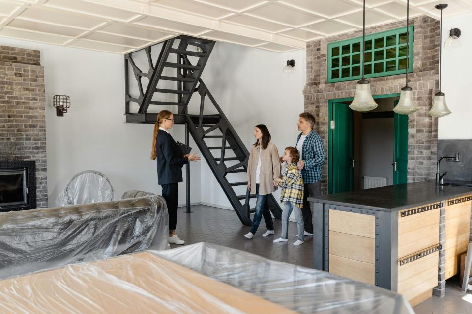 Eine Familie erkundet ein neu gekauftes Haus und wird von ihrem Immobilienmakler ins Haus geführt.